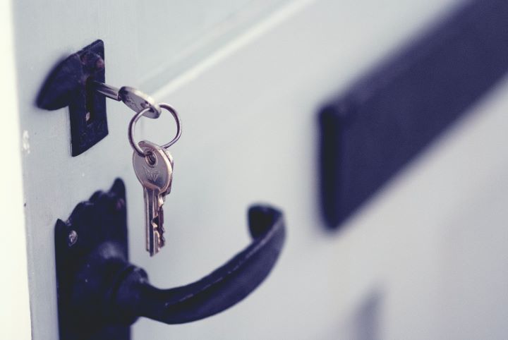 A set of keys hanging from a front door lock.