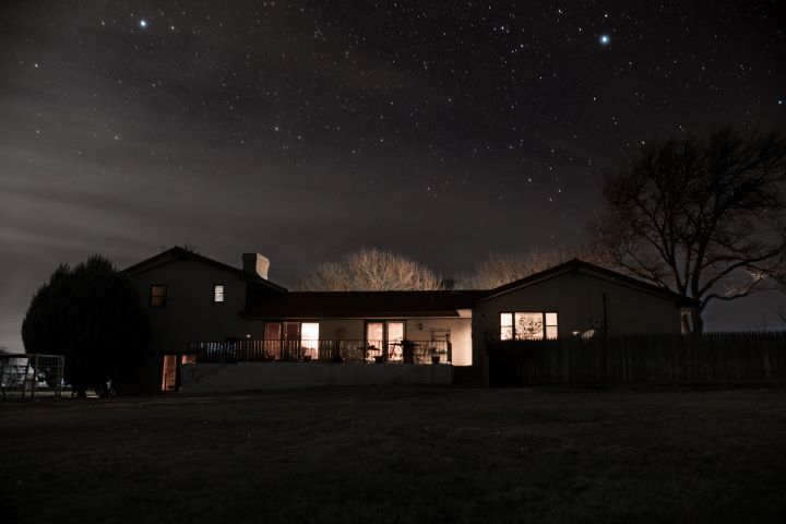 A house at night with the lights on in the windows.