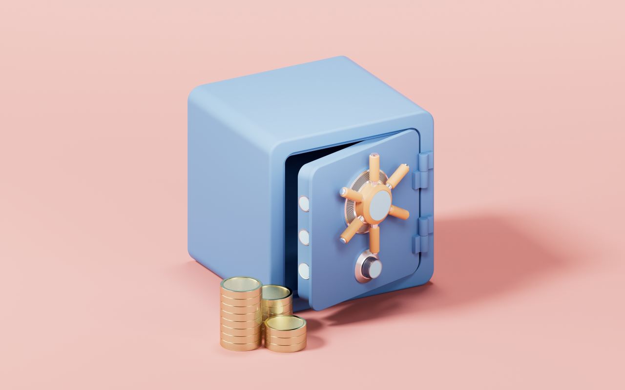 a blue safe on a pink backdrop. the safe is open slightly and there are coins as in front of it