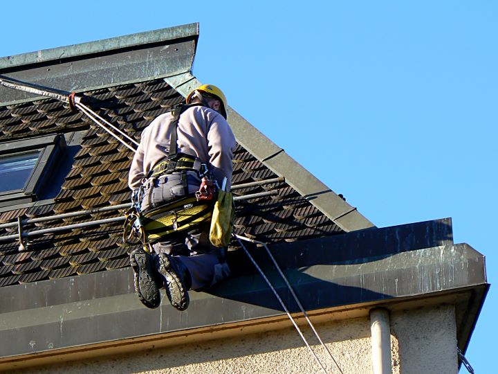 a man is harnessed and working on a roof.
